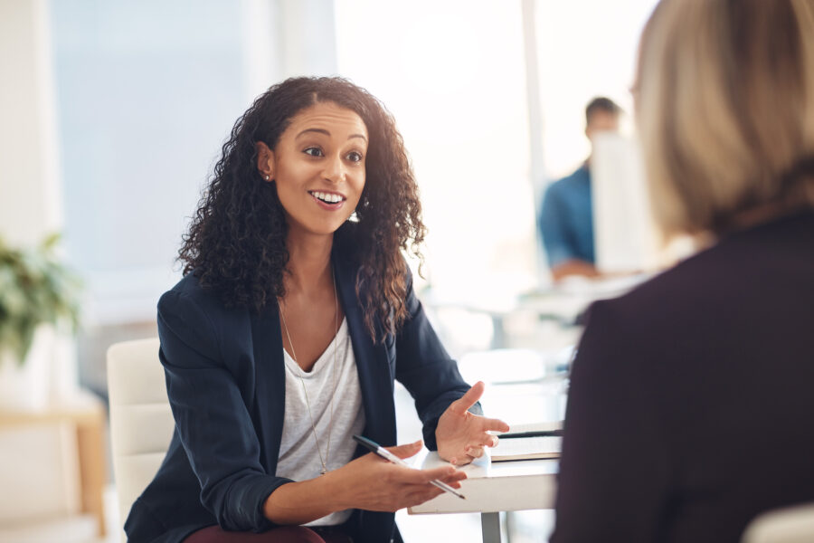 Interview with a happy, excited and confident human resources manager talking to a shortlist candidate for a job. Young business woman meeting with a colleague or coworker in her office at work.