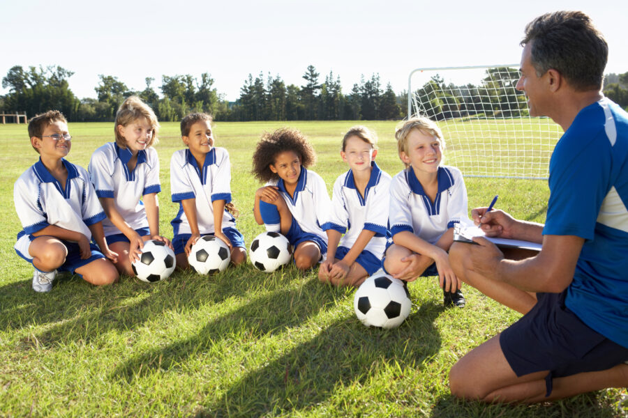 Group Of Children In Soccer Team Having Training With Coach