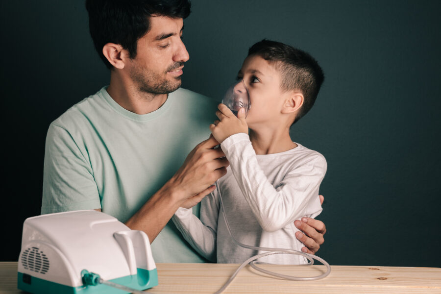 Portrait of father and son using domestic inhaler / nebulizer