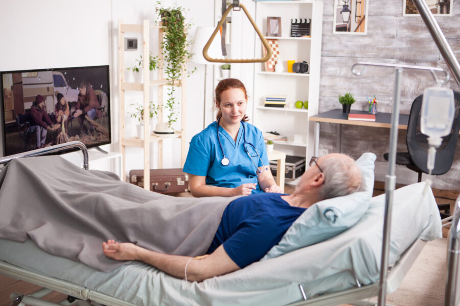 Female doctor with stethoscope sharing comfort to old man in nursing home.